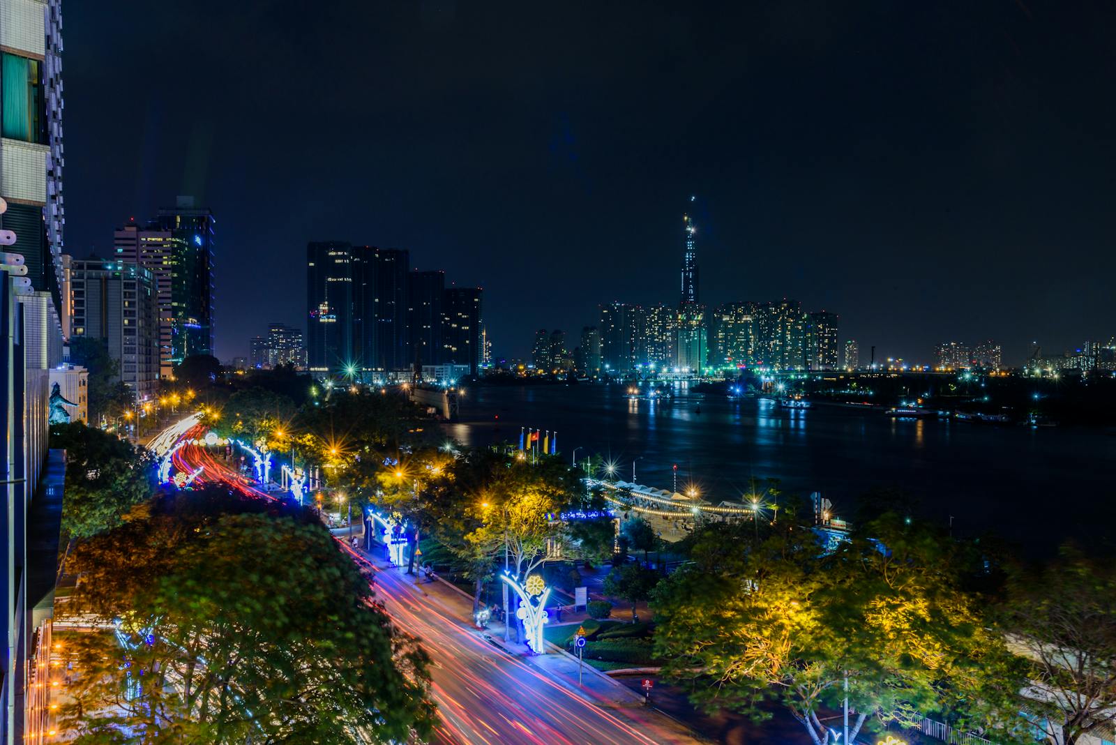 Photo by Marcus Nguyen Stunning nighttime view of Ho Chi Minh City's skyline with illuminated roads and skyscrapers by the Saigon River.
